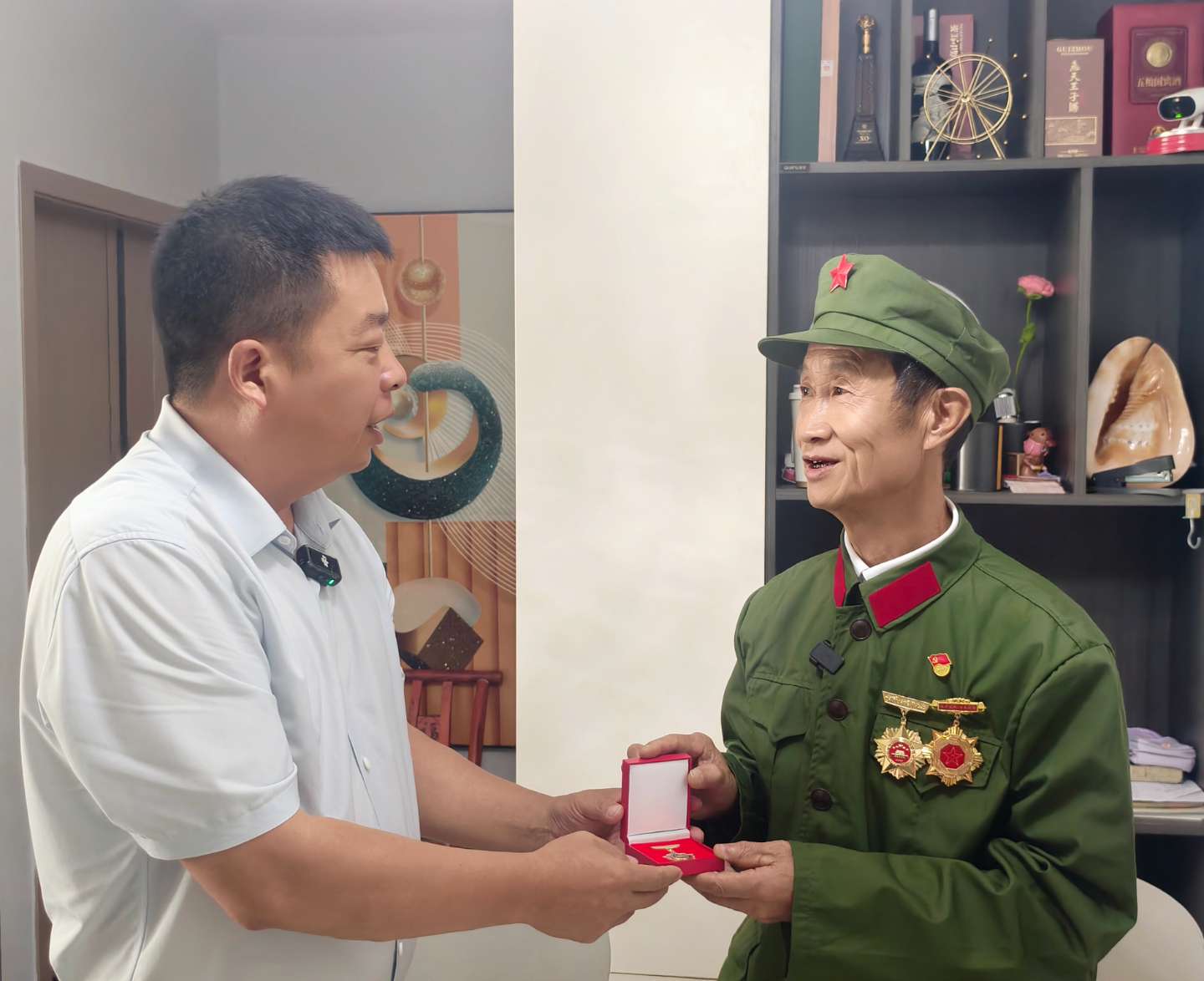 吴庆武（左）将修好的纪念章，交给杨昌应（右）。田金凤 摄.jpg